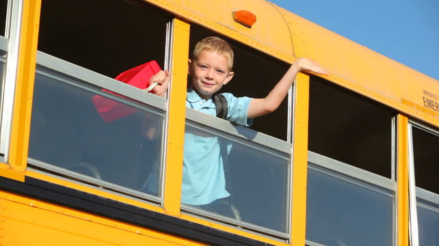 Young boy waves out window of school bus