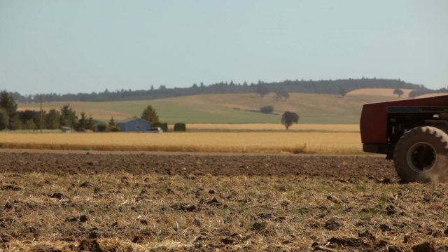 Tractor pulling plow across dusty field