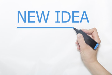 Hand writing new idea with blue marker on transparent wipe board