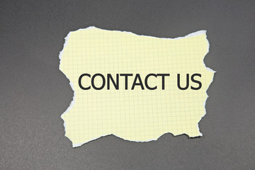 Torn yellow paper with word Contact Us. black sugar paper background