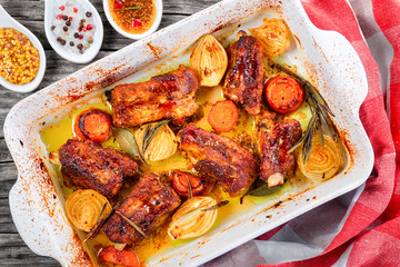 roasted ribs in a baking dish with onion, carrots, spices - obrazy, fototapety, plakaty