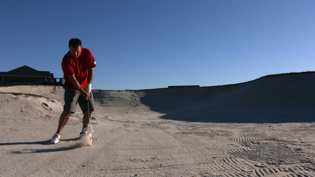 Golfer hits ball from sand trap, slow motion