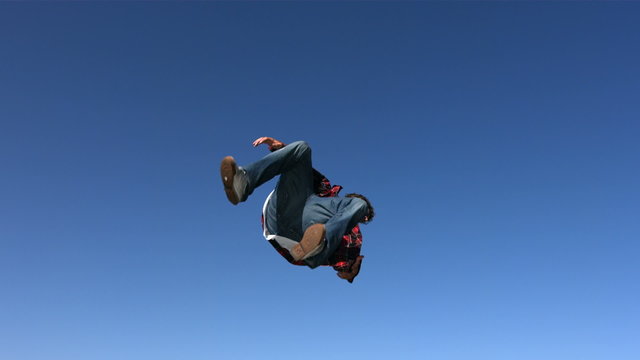 Teen boy flips in sky, slow motion
