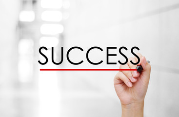Hand holding pen and success word on blur background