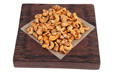 Bunch roast cashew nut spices on dark brown serving board.