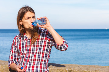 Man long hair relaxing by seaside drinking water