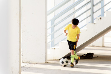 Boy play football under the empty building