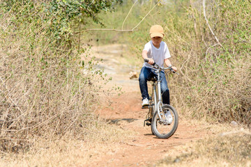 Little boy ride bicycle on the rock road.