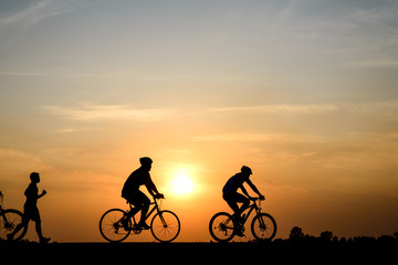 Obraz na płótnie Canvas Silhouette of cyclist with friend motion on sunset background