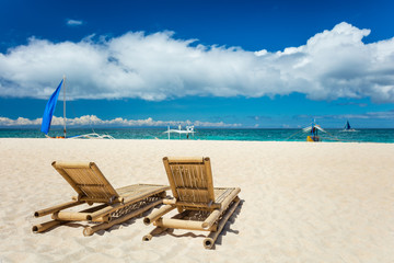Tropical beach with chaise longues in foreground