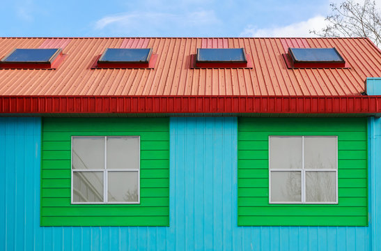 Painted colorful wall of residential building against blue sky.