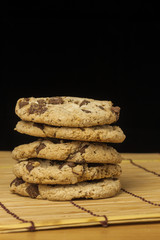 Stack of Chocolate chip cookies on wooden with black background.