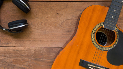 Fototapeta premium Top view workspace with headphone and acoustic guitar on wooden table.