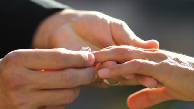 Groom puts ring on brides finger, closeup