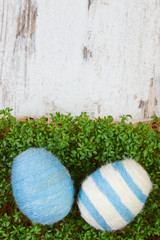 Easter eggs wrapped woolen string and green cress on wooden background, copy space for text, decoration for Easter