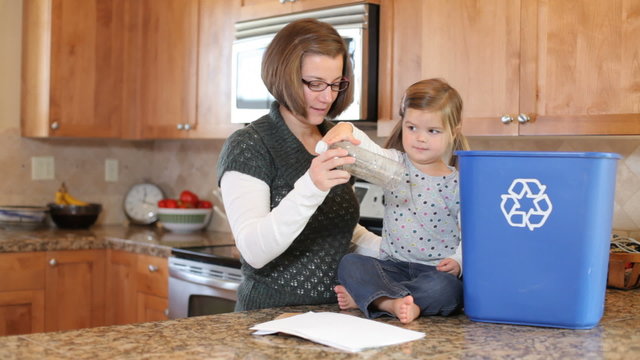 Mother and young daughter in kitchen recycling