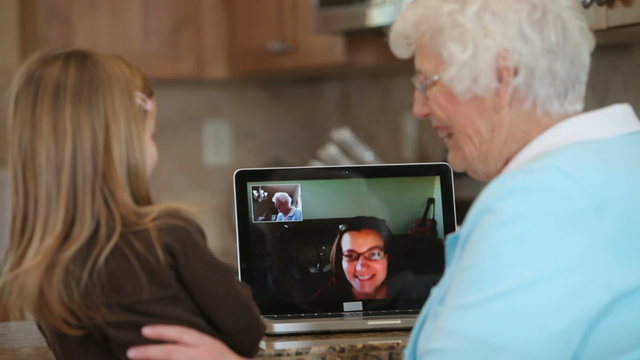Great Grandmother and granddaughter wave to family on computer