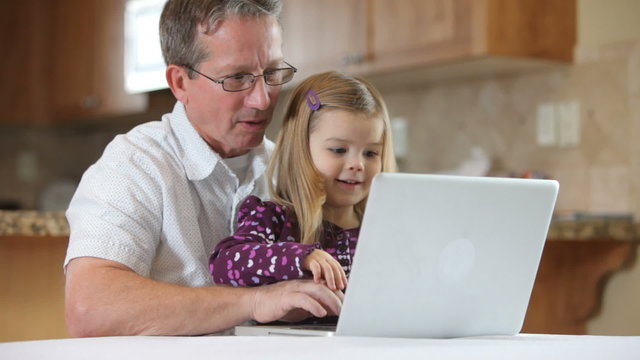 Grandfather using laptop with granddaughter