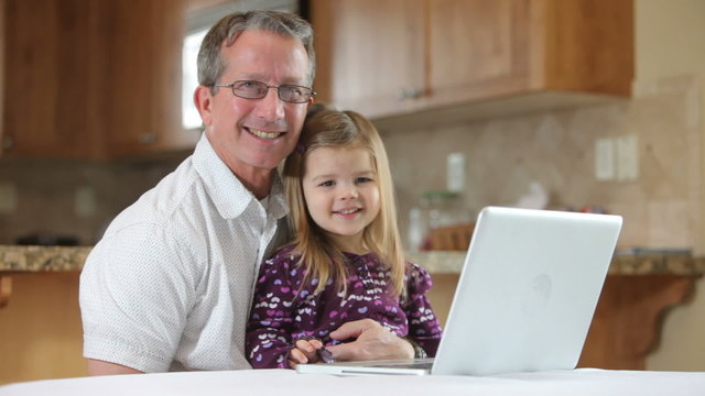 Young girl working on laptop computer with Grandfather