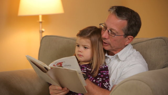 Grandfather reading book with granddaughter