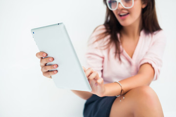 beautiful young woman in sunglasses sitting in a cafe drinking coffee/tea and work on your tablet on the Internet