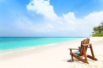 Fototapeta na wymiar Lonely beach chair with hat and slippers at tropical beach, summ