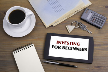INVESTING FOR BEGINNERS. Text on tablet device on a wooden table