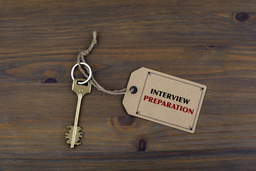 Key and a note on a wooden table with text -Interview Preparatio