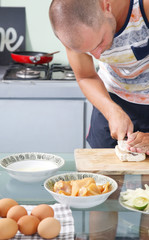 Man preparing meal in the kitchen - cutting tempeh