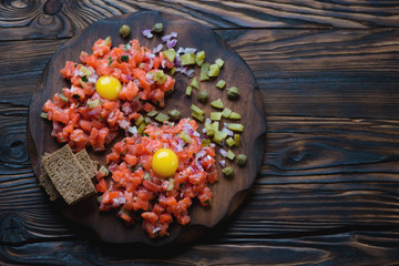 Rustic wooden serving board with salmon tartar, above view