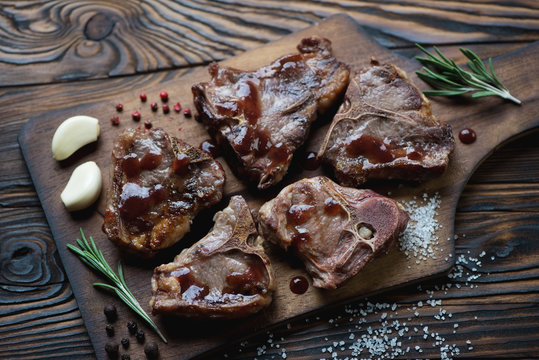 Grilled T-bone lamb steaks on a wooden serving board, close-up