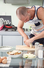 Man preparing meal in the kitchen - cutting tempeh