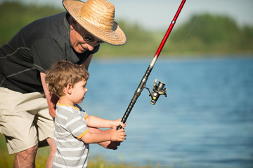 Little boy fishing with grandpa