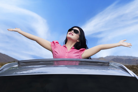 Cheerful woman standing on the sunroof