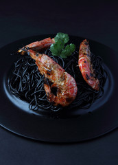 Spaghetti with king prawns on the black dish..