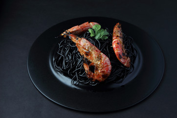 Spaghetti with king prawns on the black dish..