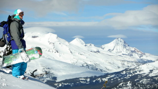 Snowboarder looks out from mountain top