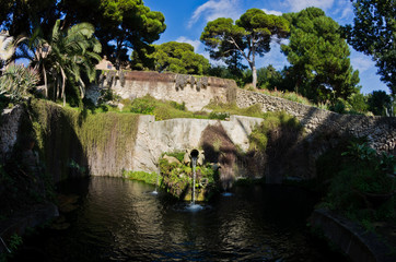 Fototapeta na wymiar Fountain in a park with water flowing from an old amphora, Cagliari, Sardinia, Italy