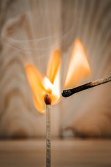 match is ignite on a blurry wood background. Selective focus.