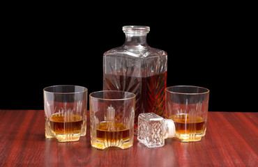 Decanter and three glasses with whiskey on a wooden table