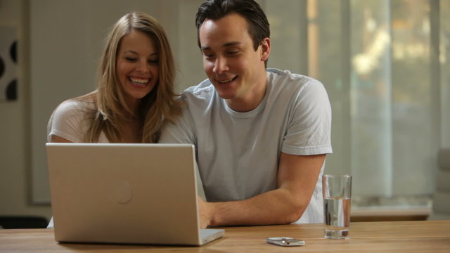 Couple in kitchen looking at laptop computer together