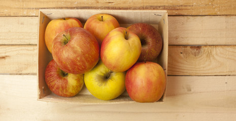 Bunch of apples in box on wooden board, with copyspace