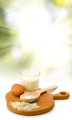 milk, egg, flour, spoon and board on sun background