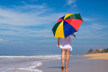 Girl with an colorful  umbrella on the sandy beach