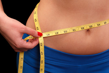Girl after exercise meter measures your waist on a black background.