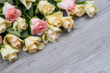 Pink and yellow roses bouquet over wooden table