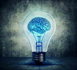 Human brain glowing inside a light bulb. Blue shining lamp on gray background. Emergence of the...
