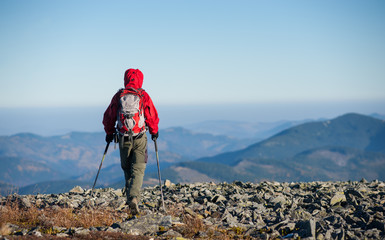 Male sportsman backpaker walking on the rocky top of the mountain with beautiful mountains on...