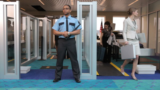Airport security guard stands watch at metal detector