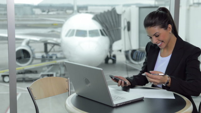 Business woman with laptop and cell phone in airport
